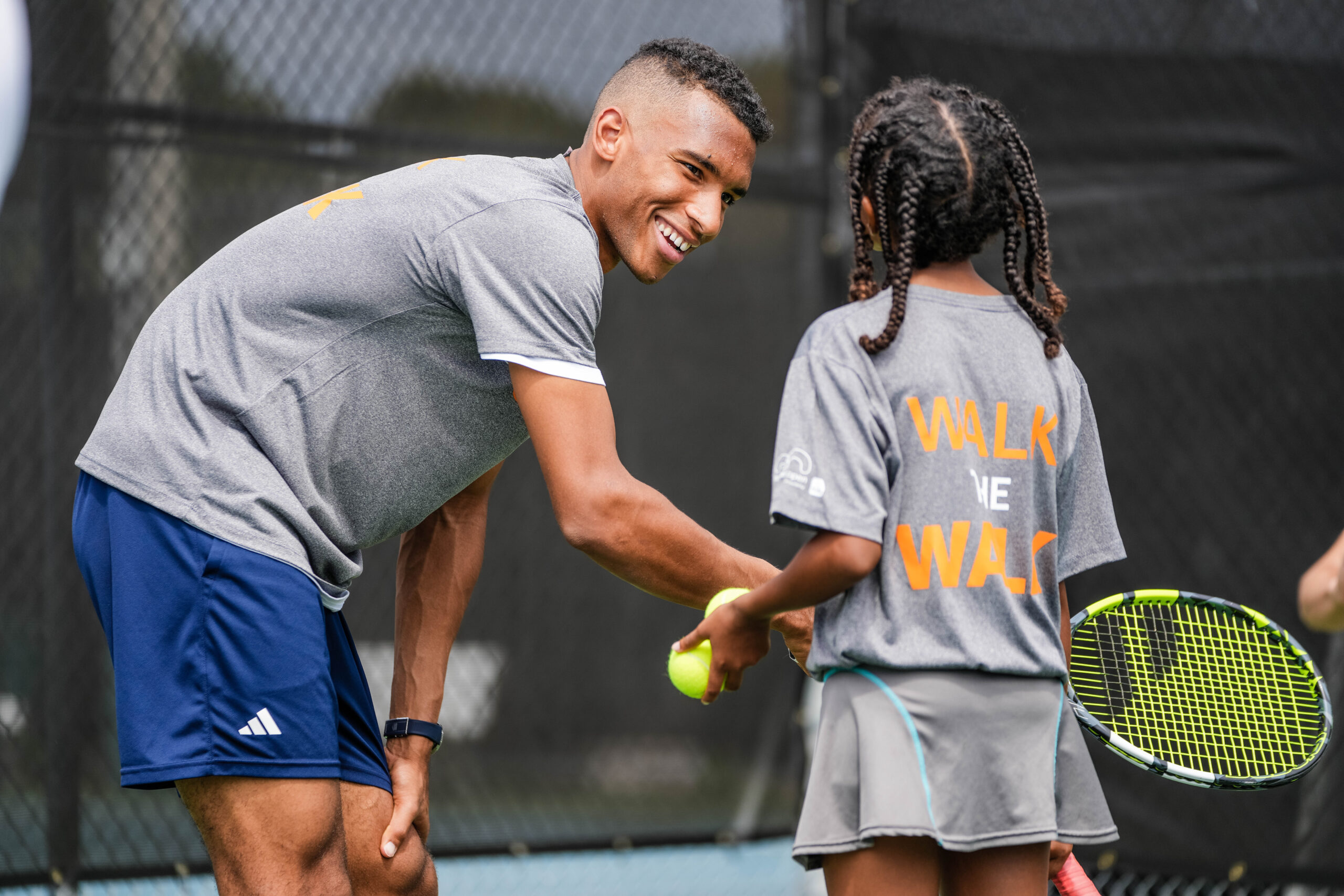 Felix Auger-Aliassiime has fun and smiles with a young participant of the tennis clinic during the Big Brothers, Big Sisters event at Moore Park in Miami on March 20, 2023.