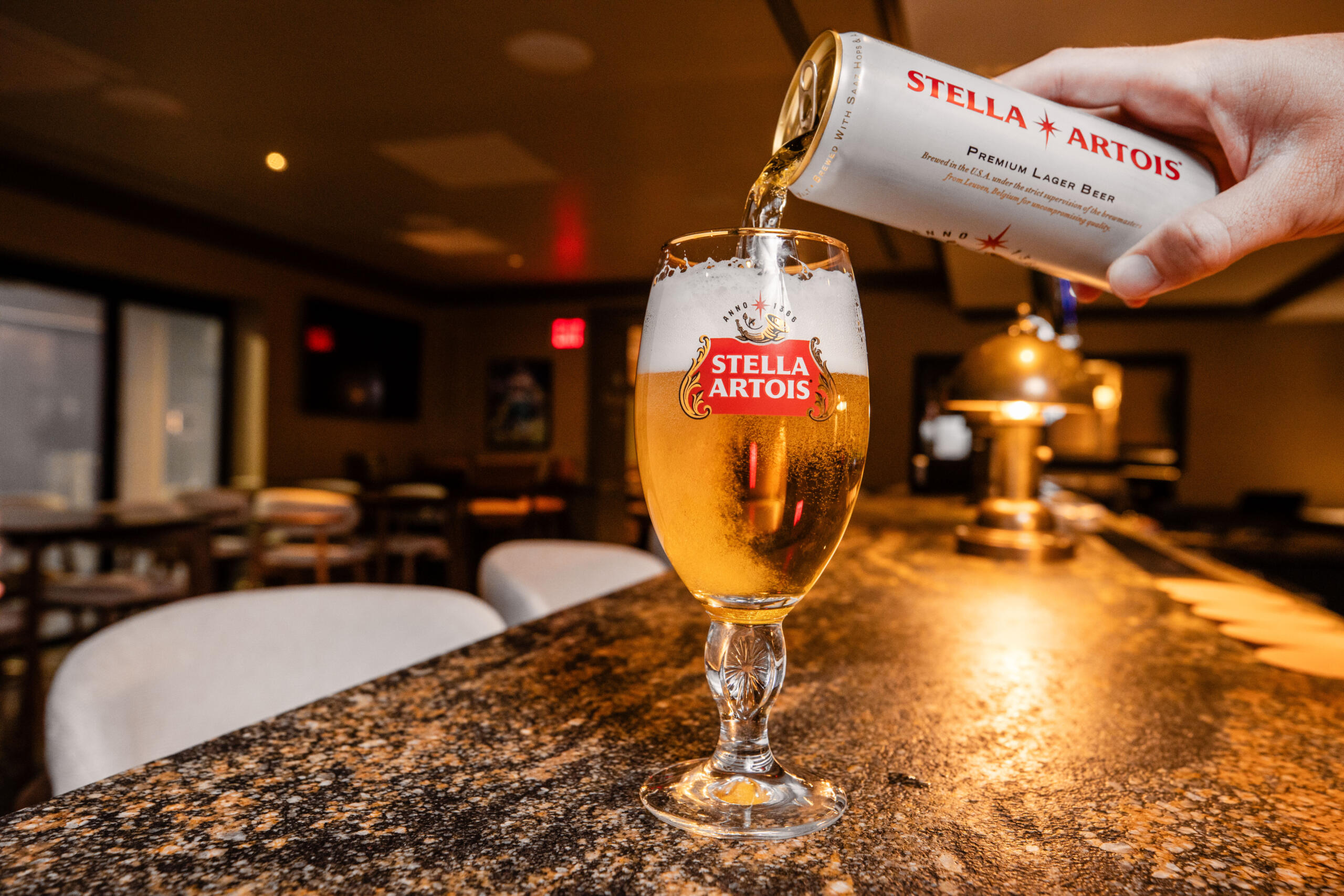 Hand pouring Stella beer can into a glass at the bar
