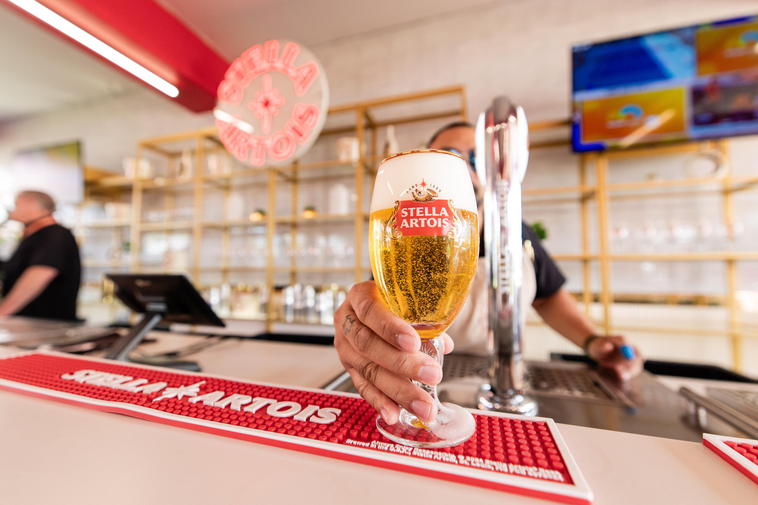 Bartender slides a Stella Artois beer across the bar