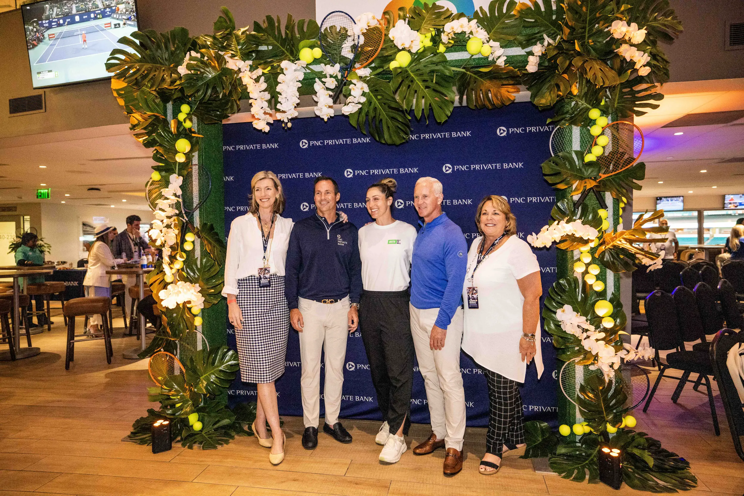 private event space 1-2 Five guests pose in front of a PNC Private Bank backdrop beneath a decorative arch inside a hospitality space at the Miami Open.